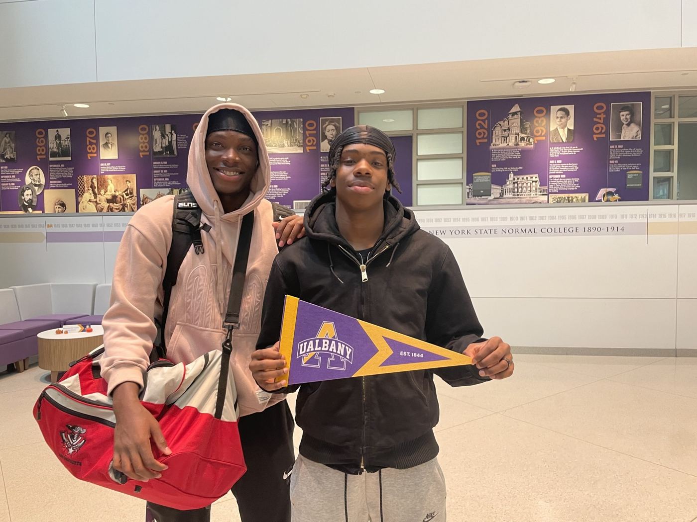 Two students holding a UAlbany pennant on a campus visit, Fall 2025